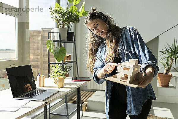 Architekt zeigt auf Modell bei Videokonferenz im Heimbüro