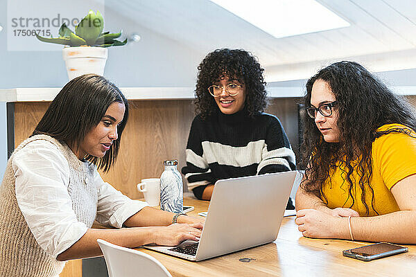 Junge Geschäftsfrauen schauen Kollegen zu  die im Coworking-Büro diskutieren