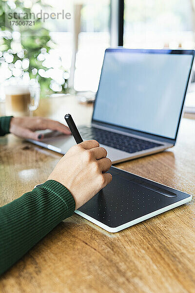 Geschäftsfrau mit Laptop und Grafiktablett im Café