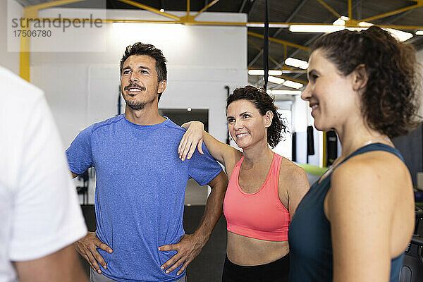 Lächelnde Freunde schauen Sportler im Fitnessstudio an