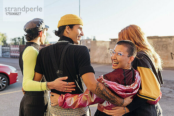 Glückliche Frau mit Freunden auf der Straße im Arm