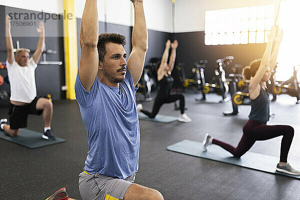 Sportler mit erhobenen Armen trainieren im Fitnessstudio
