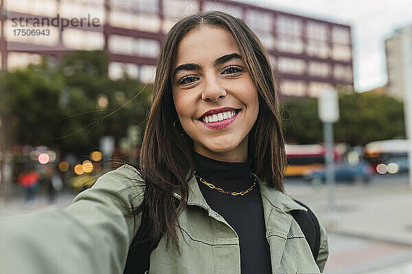 Lächelnde junge Frau  die ein Selfie in der Stadt macht