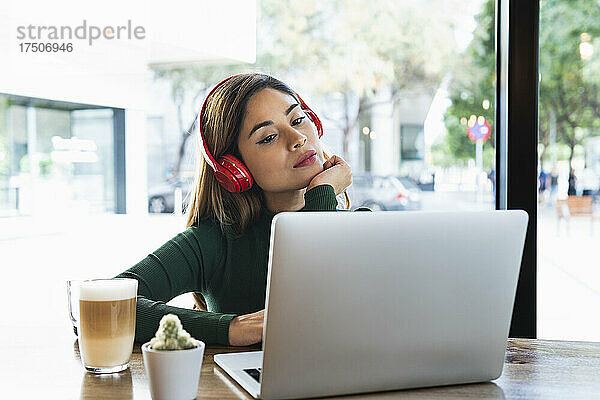 Nachdenkliche Geschäftsfrau mit Laptop am Cafétisch
