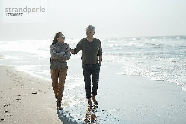 Älterer Mann und Tochter gehen gemeinsam am Strand spazieren
