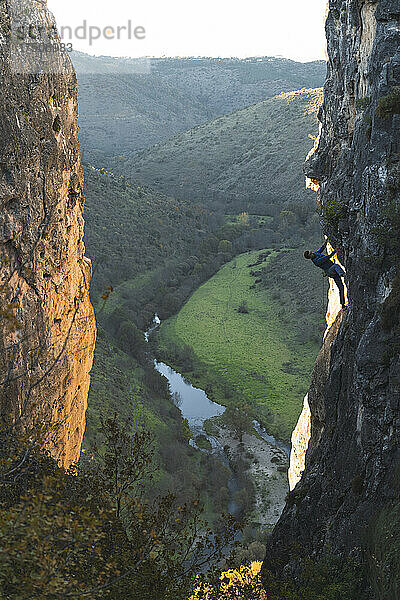 Aktiver Wanderer klettert bei Sonnenuntergang auf den Felsberg