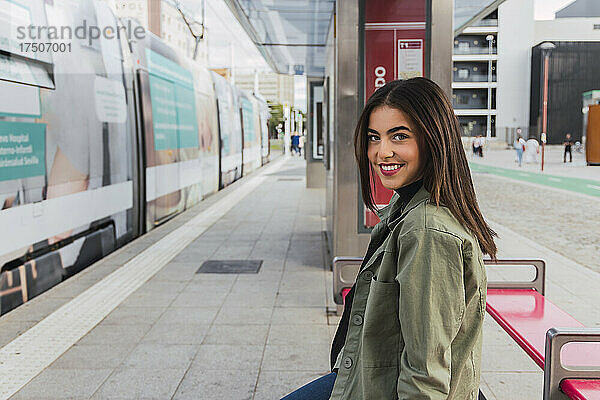 Junge lächelnde Frau am Bahnsteig der Straßenbahn