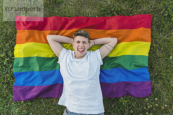 Woman with hands behind head relaxing on rainbow flag