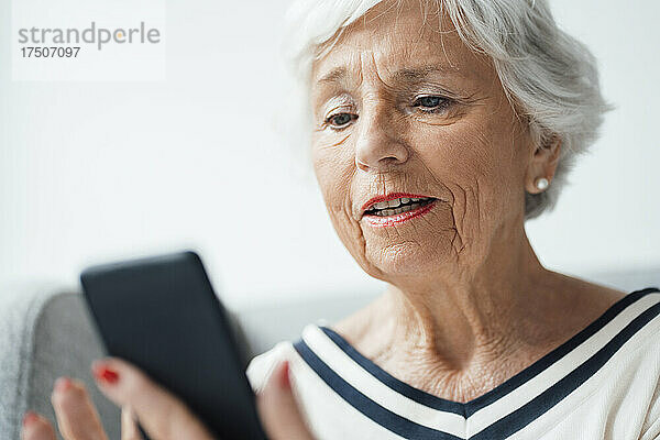 Ältere Frau hält Smartphone zu Hause