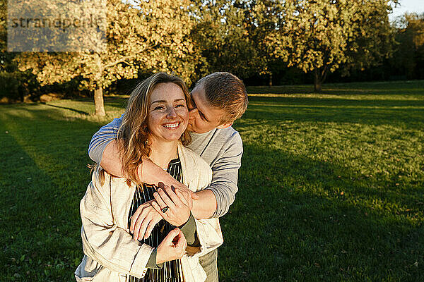Mann küsst blonde Freundin im öffentlichen Park