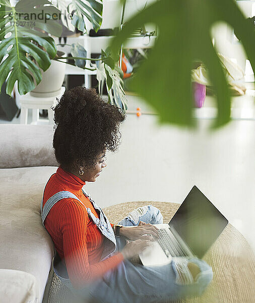 Frau mit lockigem Haar benutzt Laptop zu Hause