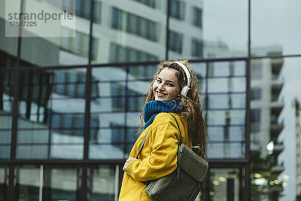 Lächelnde junge Frau mit Rucksack in der Stadt