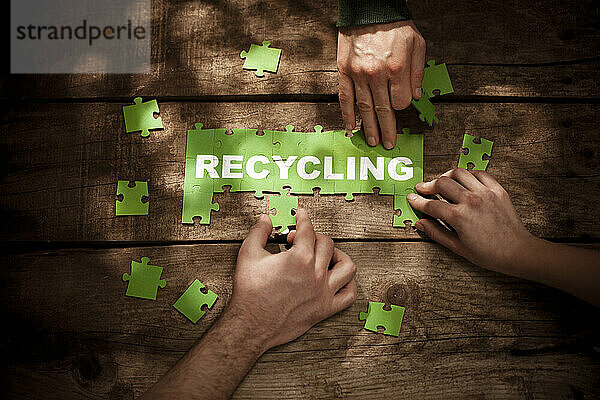 Freunde lösen Rätsel mit Recycling-Wort am Tisch