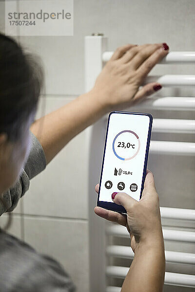 Frau regelt die Temperatur per Handy am Heizkessel