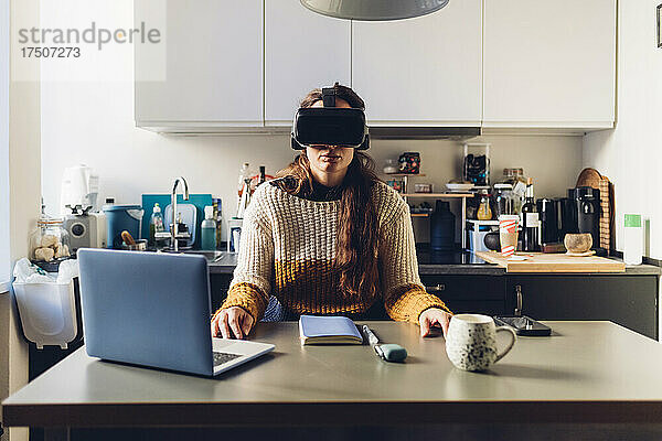 Frau mit Virtual-Reality-Headset sitzt zu Hause am Schreibtisch