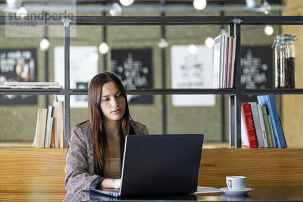 Junge Geschäftsfrau benutzt Laptop im Café