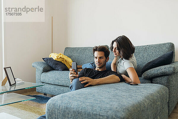 Junges Paar macht Selfie per Smartphone im heimischen Wohnzimmer