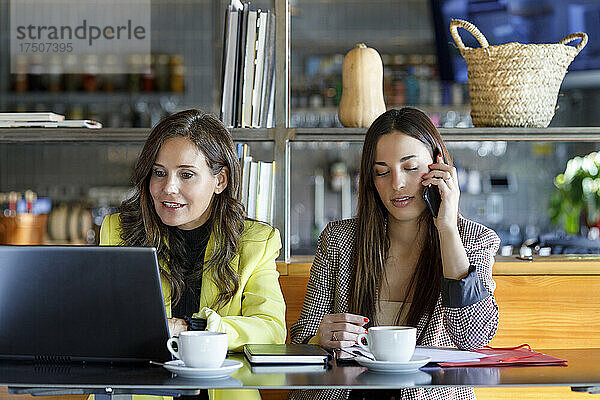 Kollegen mit Laptop und Smartphone arbeiten am Cafétisch