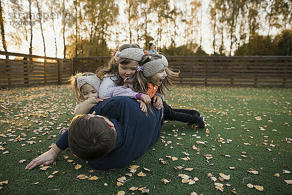 Geschwister spielen im Herbst mit Vater auf dem Rasen