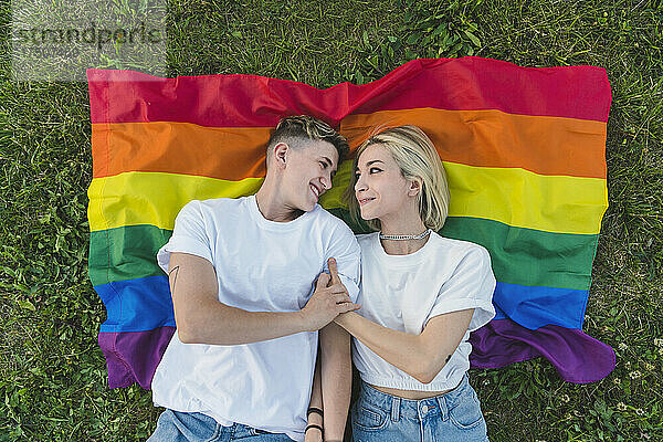 Lesbisches Paar hält Hände auf Regenbogenfahne