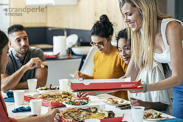 Lächelnde Geschäftsfrau mit Pizzakarton von Kollegen in der Mittagspause