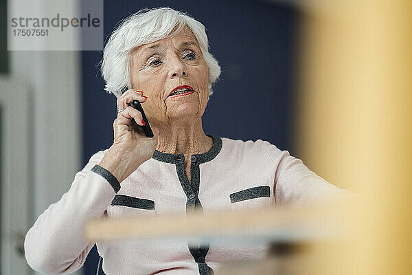 Ältere Frau telefoniert zu Hause mit dem Handy