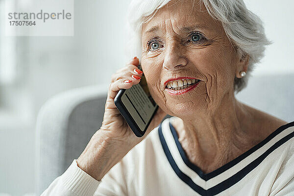 Lächelnde Frau  die zu Hause mit dem Smartphone spricht