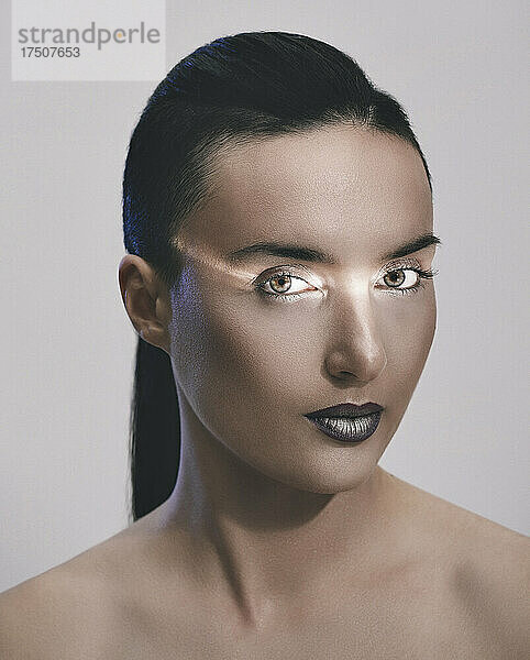 Frau mit Lichtreflexion im Gesicht vor grauem Hintergrund