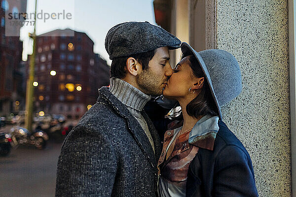 Junges  liebevolles Paar küsst sich mit geschlossenen Augen in der Stadt