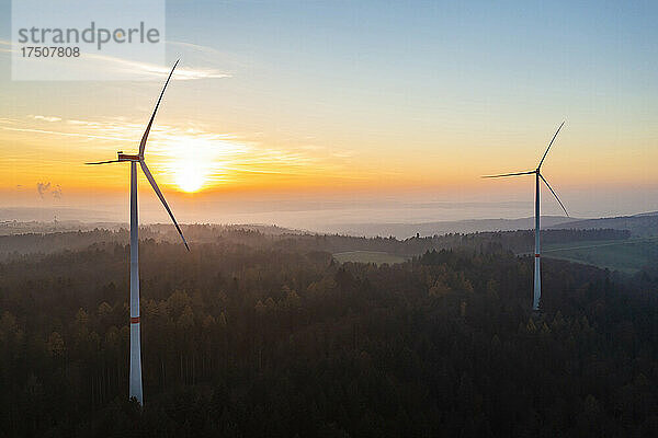 Luftaufnahme eines Windparks im bewaldeten Schurwald-Gebirge bei Sonnenuntergang