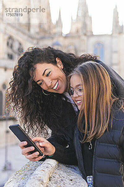 Lächelnde Mutter und Tochter mit Smartphone in der Kathedrale von Burgos  Burgos  Spanien