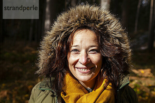 Lächelnde Frau mit Pelzmütze im Wald