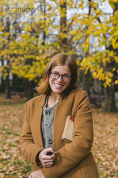Glückliche Frau mit Buch im Herbstpark
