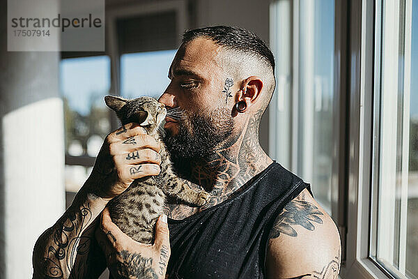 Mann mit Tätowierung küsst Katze zu Hause