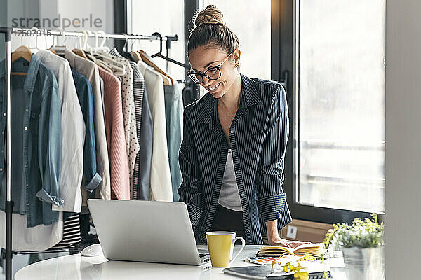 Lächelnder Modedesigner mit Laptop im Büro