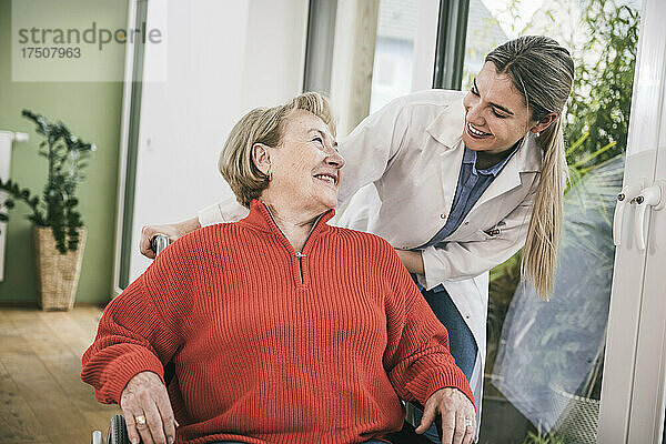Behinderte Frau lächelt die Krankenschwester an  die dahinter steht