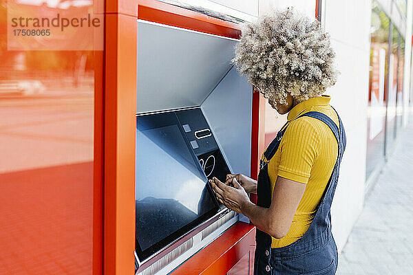 Frau mit Afro-Frisur am Geldautomaten