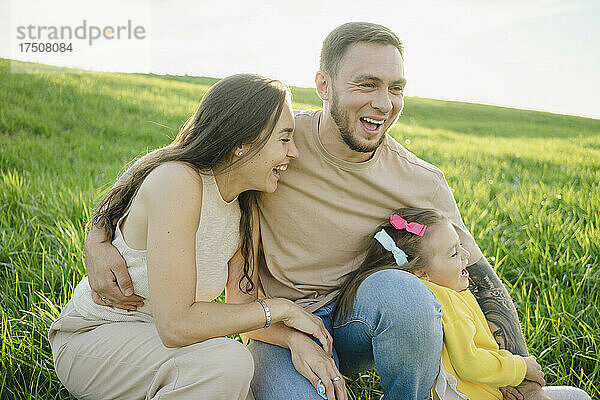 Verspieltes Paar genießt es mit seiner Tochter im Gras