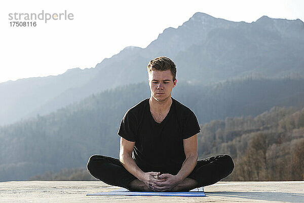 Konzentrierter Mann meditiert im Lotussitz auf einer Trainingsmatte