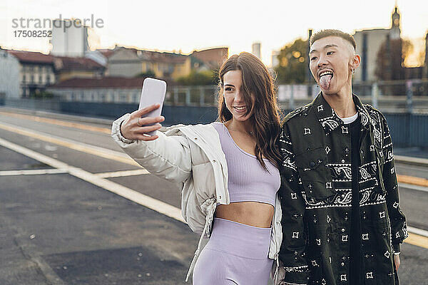 Frau macht Selfie mit Mann  der die Zunge herausstreckt