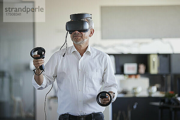 Geschäftsmann spielt mit virtuellem Headset am Arbeitsplatz