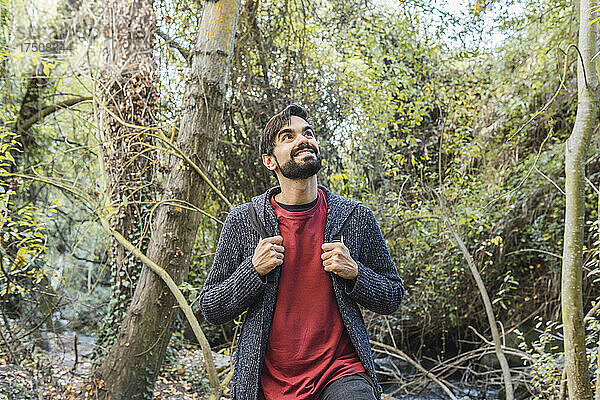Lächelnder junger Mann beim Wandern im Wald