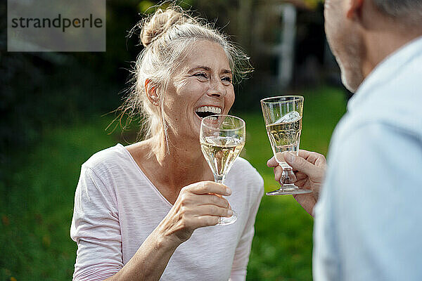 Lächelnde Frau trinkt Champagner mit Mann im Hinterhof