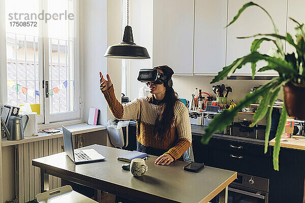 Frau gestikuliert mit Virtual-Reality-Headset zu Hause