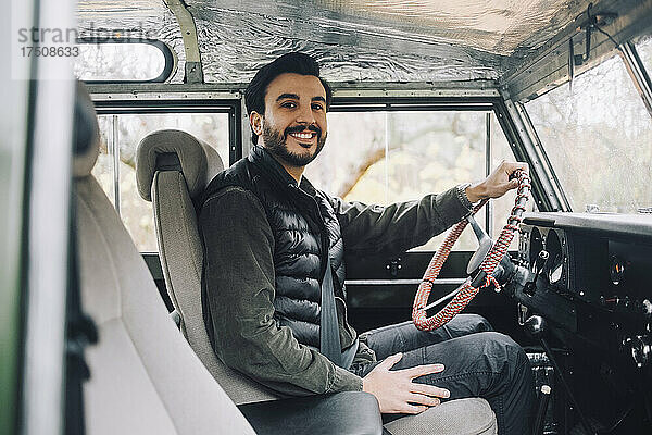 Porträt eines lächelnden Mannes  der in einem Geländewagen sitzt