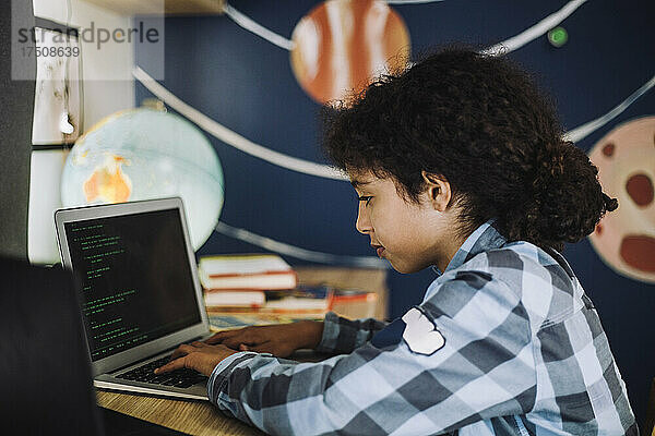Konzentriertes Mädchen lernt zu Hause am Laptop Programmieren