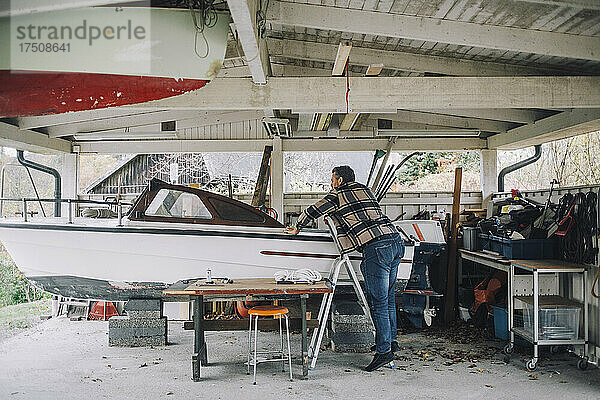 Älterer Mann repariert Schnellboot in Garage