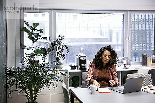 Schwangere Frau arbeitet am Schreibtisch im Büro