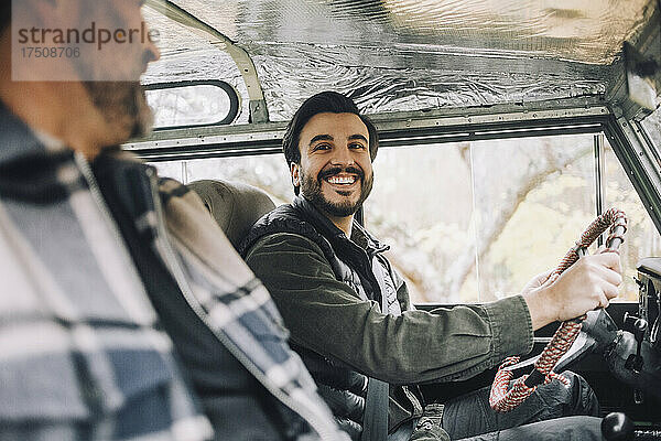 Glücklicher Sohn im Gespräch mit seinem Vater  während er in einem Geländewagen sitzt