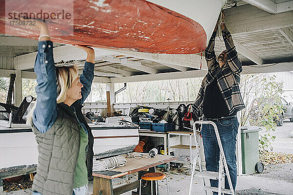 Älterer Mann bindet ein nautisches Schiff  während eine Freundin ihm in der Garage hilft